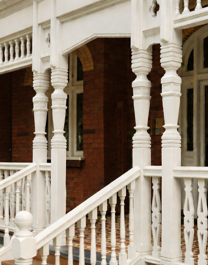 White porch railing and steps of a house with brick walls